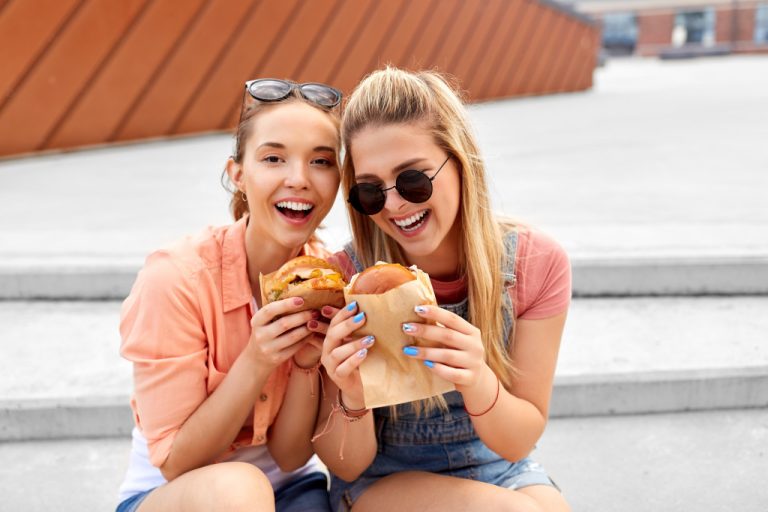 friends females eating burger on the go outdoors